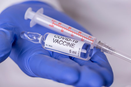 Health care specialist holding a covid-19 vaccine vial and syringe; doctor holding novel...