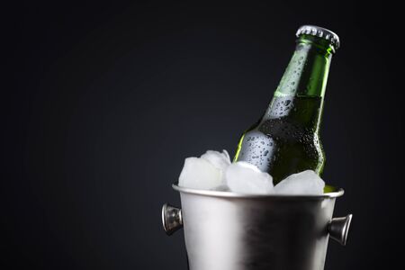 Bottle of beer in an ice bucket filled with ice cubes placed on a bar counter with copy spaceの写真素材