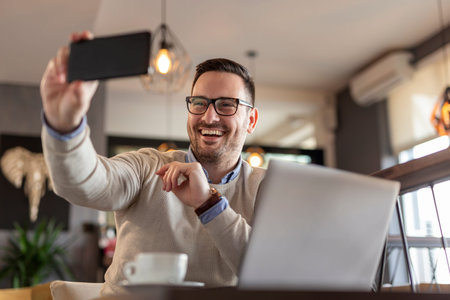 Male freelancer working remotely from a restaurant, having a conference call using smart phone