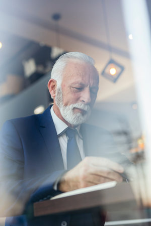Senior businessman working, taking notes in a planner, serious and pensive