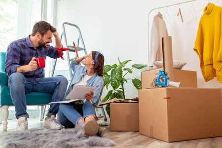 Couple in love drinking coffee and having fun while searching for home redecoration ideas using...