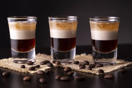 Three shots of B-52 cocktail placed on a bar counter, decorated with roasted coffee beansの写真素材