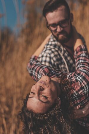 Couple in love having fun outdoors, man carrying woman in his arms, spinning around together and laughingの写真素材