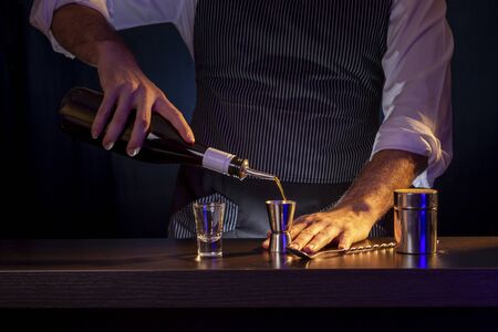 Bartender making B-52 layered cocktail shot, pouring coffee liqueur into a measuring cupの写真素材