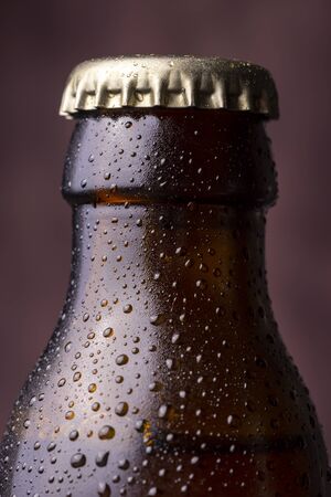 Detail of cold, wet beer bottle with a cap, dew and condensate water droplets on the surface of the glassの写真素材