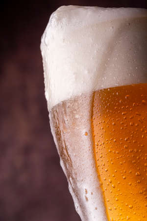 Pint of ice cold light beer with froth leaking over the glassの写真素材