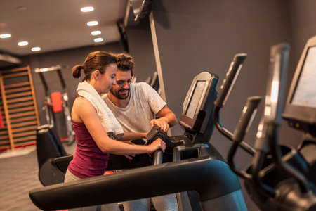Young couple working out in gym, cycling on bike machines, doing cardio training sessionの写真素材