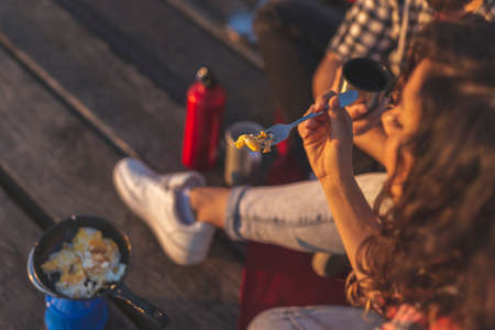 High angle view of a couple camping at the docks, making and eating dinner and enjoying a sunsetの写真素材