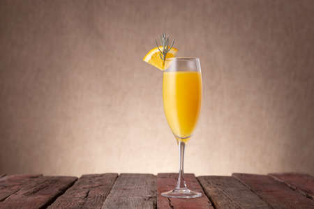 Mimosa cocktail in champagne glass with orange juice and sparkling wine decorated with lavender leaves and orange slicesの写真素材