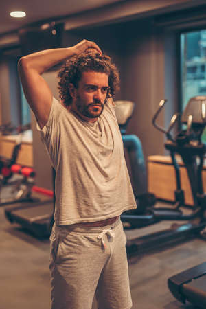 Handsome young man stretching out after hard workout in gymの写真素材