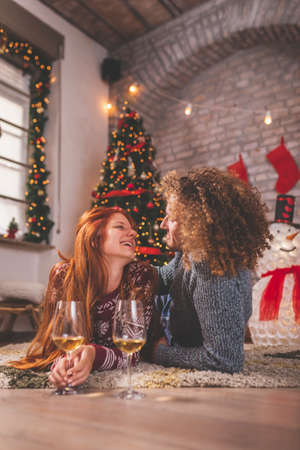 Young couple in love having fun while celebrating Christmas at home, playing the guitar, singing Christmas songs and drinking wineの写真素材