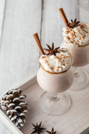 Delicious creamy homemade eggnog served in glasses with cinnamon rim decorated with anise star and...