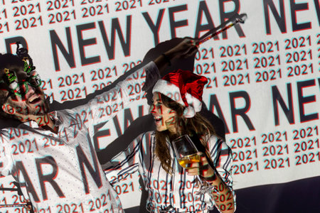 Beautiful young couple in love having fun at New Years Eve party, singing and dancing at midninght countdown; couple celebrating New Year in a nightclubの写真素材