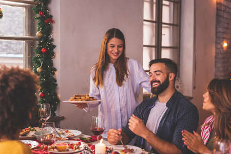 Group of friends having fun at Christmas dinner, waving with sparklers and singing Christmas songsの写真素材