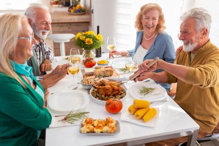 Group of senior friends having fun while celebrating Thanksgiving together at home over traditional...