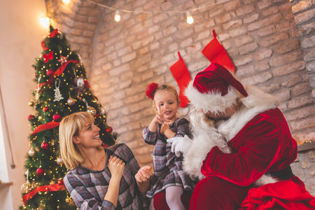 Mother and daughter sitting by the nicely decorated Christmas tree, having fun at home celebrating...