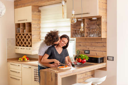 Beautiful young couple in love dancing and kissing in the kitchen, boyfriend lifting and hugging his girlfriend, having fun and relaxing at homeの写真素材