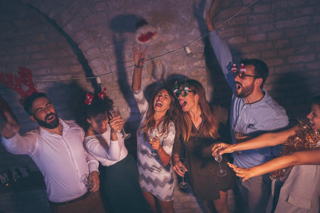 Group of friends having fun at New Year's Eve party after the midnight countdown, playing the...