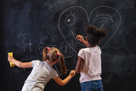 Two beautiful little girls doing math at home as part of homeschooling due to Covid 19 pandemic social distancing measures; children studying and doing homework at homeの写真素材