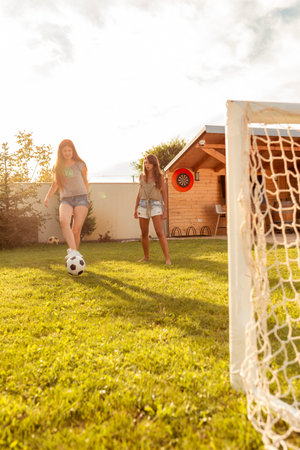Group of young friends having fun while playing football on the backyard lawn on sunny summer day;...
