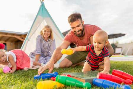Beautiful young happy family having fun spending sunny summer day camping in the backyard, parents...