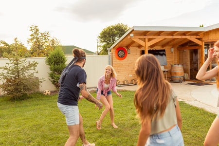 Group of cheerful young friends having fun at poolside summertime outdoor party, playing blind man's...