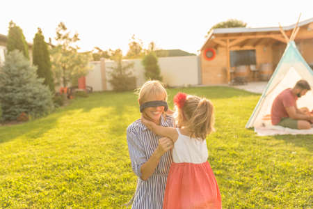 Beautiful young happy family having fun spending sunny summer day camping in the backyard, parents playing with their childrenの写真素材