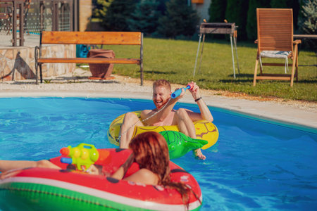 Beautiful young couple in love having fun swimming and splashing water on each other in the pool,...