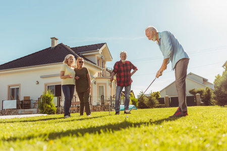 Senior people having fun playing tug of war game, spending sunny summer day outdoors; group of...