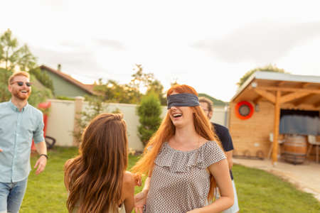 Group of young friends having fun spending summer day outdoors, playing with squirt guns, splashing water on each other, running and chasing each otherの写真素材