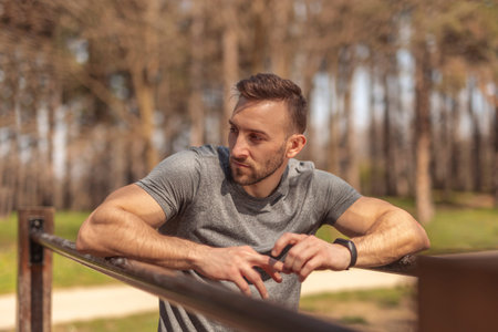 Handsome active young man taking a break while having an outdoor training session in a street workout parkの写真素材
