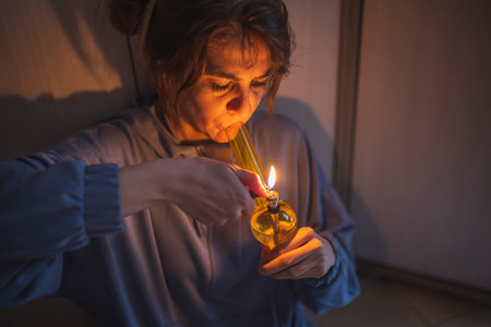 Depressed young woman sitting on the floor in the dark, drinking wine and smoking cigarette, upset and desperateの写真素材