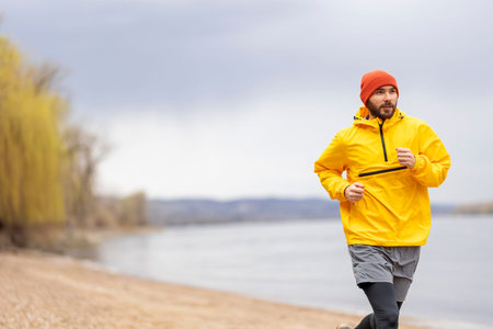 Athletic man jogging by the river on a cloudy autumn day