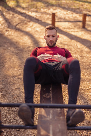 Man holding plank position while working out outdoors in street workout park on a sunny autumn day
