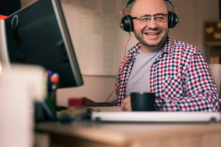 Male programmer sitting at his desk while working from home, holding head in hands, stressed out...