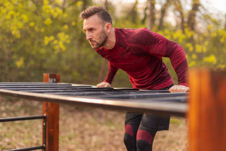 Athletic young man carrying gym bag, drinking water after an intense outdoor workout in a street workout parkの写真素材