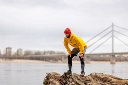 Active man jogging in the park in the morning on a cloudy autumn day, taking a break and relaxingの写真素材