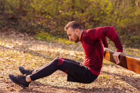 Man working out outdoors in street workout park on a sunny autumn day, doing bodyweight dipsの写真素材