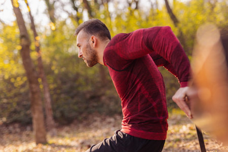 Man working out outdoors in street workout park on a sunny autumn day, doing bodyweight dips