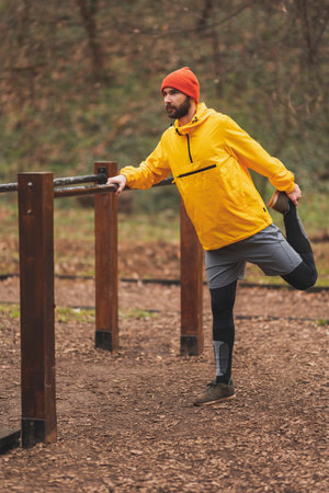 Active man stretching out before exercising in a street workout park on a cloudy winter day