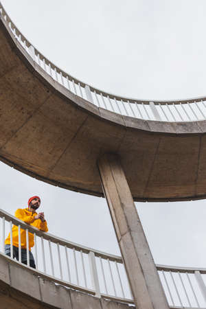 Man sitting on a fallen tree trunk, taking a break while jogging by the river on an overcast autumn day, looking at the distance pensivelyの写真素材