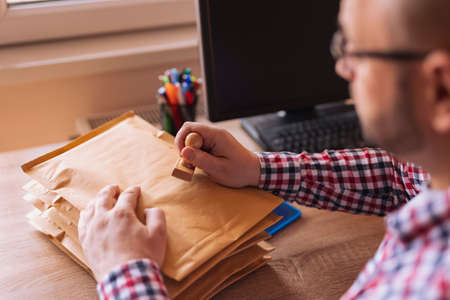 Man sending mail; small business owner packing products for delivery; entrepreneur getting online store orders ready for shippingの写真素材
