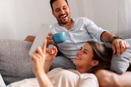Beautiful young couple in love relaxing at home, lying and hugging on the couch