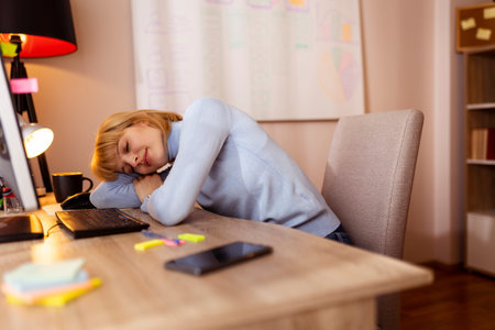 Woman sitting at her desk an office, taking a lunch break eating pizza