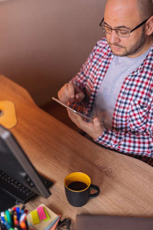 Small business owner sitting at his desk in home office, packing product for delivery; entrepreneur packaging online store orders for shippingの写真素材