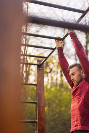 Athletic man doing push ups while exercising in street workout park on a sunny spring day