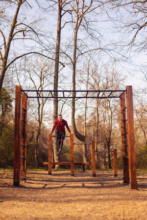 Athletic man doing push ups while exercising in street workout park on a sunny spring day