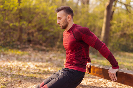 Athletic man doing push ups while exercising in street workout park on a sunny spring day