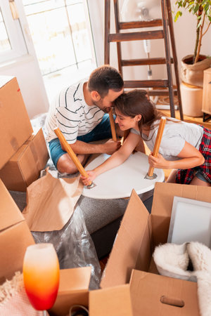 Couple in love installing coffee table while moving in new house; husband and wife moving in new...