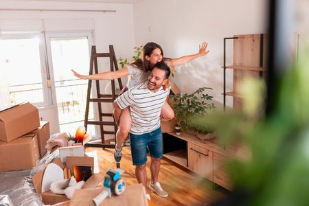 Couple in love having fun while moving in new home, searching for apartment redecoration ideas using...